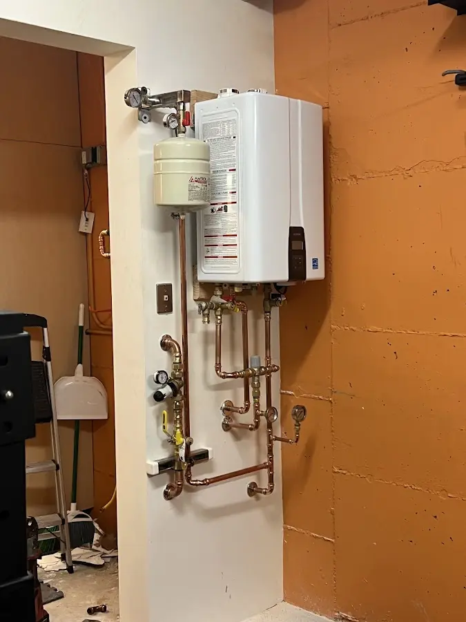 Plumbing technician inspecting water heater connections in De Soto